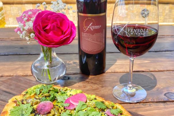 A pizza with a bottle of red wine