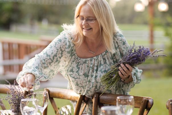 A woman decorating an outdoor feast with lavender flowers.