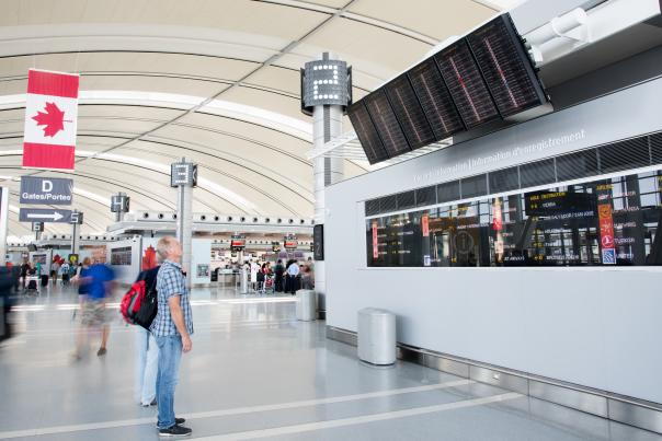 Inside Pearson International Airport departures level, man looking at information board