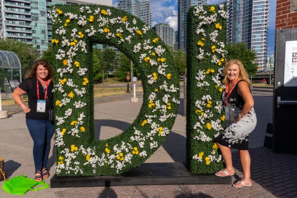 DI Attendees at opening reception in front of 'DI' flower signage