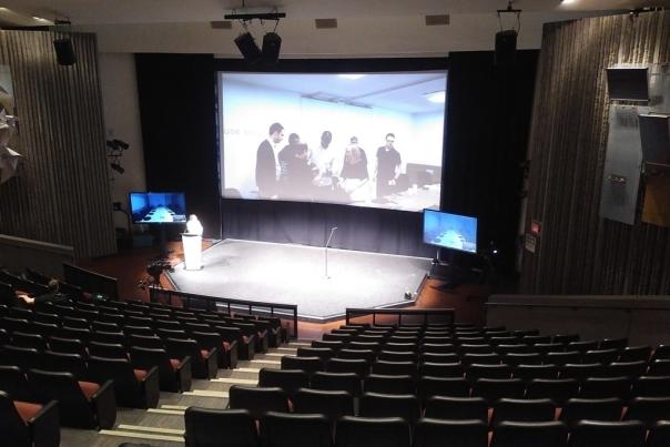 A view inside the Ontario Science Centre auditorium with theatre-style seating and big screen behind the stage