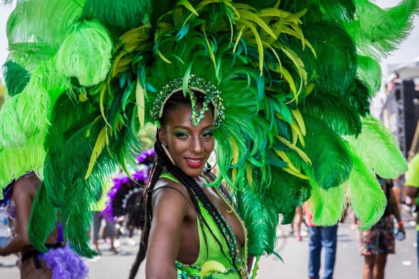A performer at the Toronto Caribbean Carnival wearing a green feathered costume and headpiece while participating in the parade