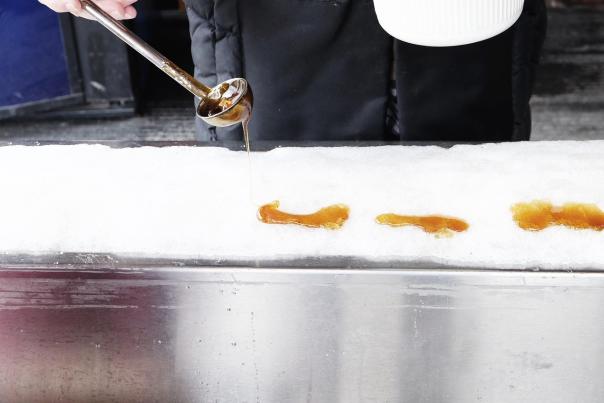 Maple syrup being poured on to snow at a sugar shack.
