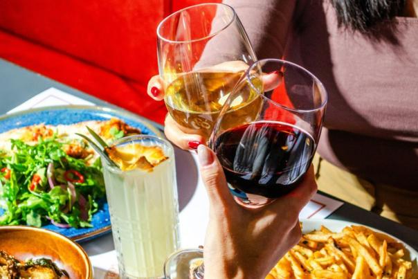 Two people clinking wine glasses together at dinner