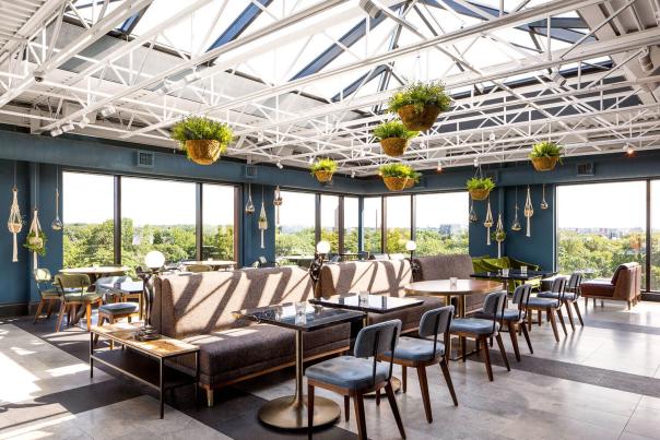 The Broadview Rooftop at daytime, interior shot with tables chairs and hanging plants