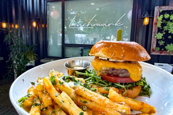 Benchmark burger with melted cheddar, tomato and arugula, served with seasoned fries at Benchmark Restaurant in Santa Ana.
