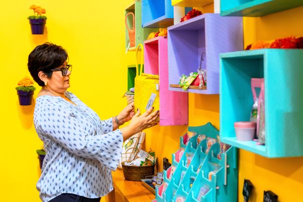 Person shopping at Collective 2one9, exploring colorful handmade goods and unique decor displayed on vibrant shelves.