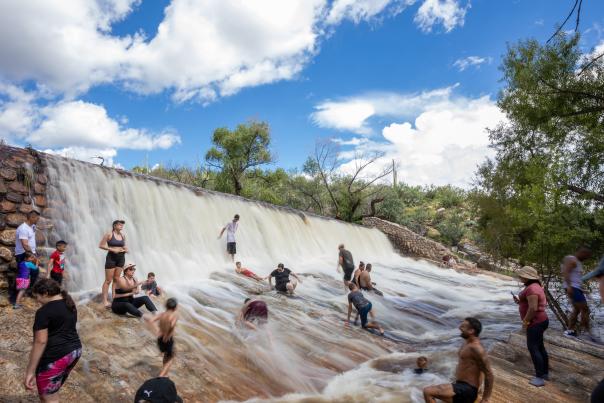 People cooling off under a water fall in Sabino Canyon