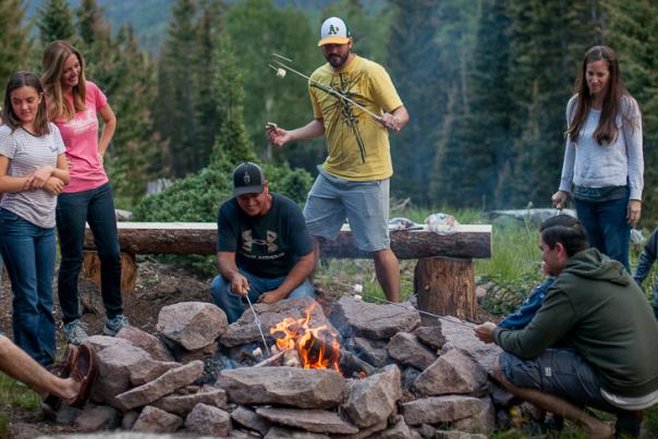 People gathered around a fire roasting marshmallows in the Tushar Mountains