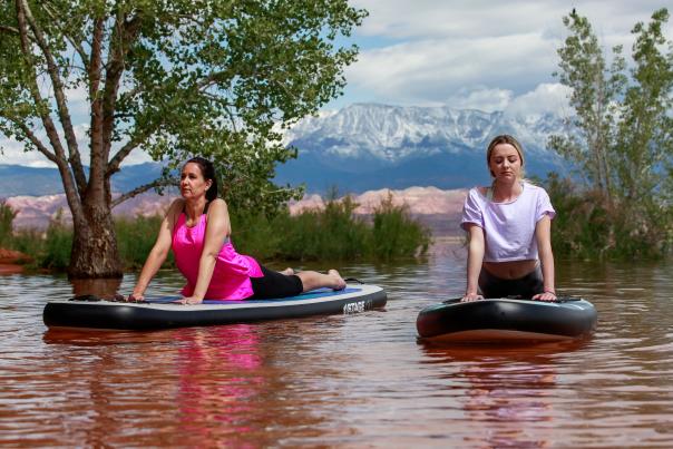 Two women doing yoga on a stand up paddleboard