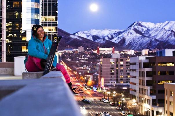View of downtown Salt Lake City with snow covered peaks and full moon in the background.