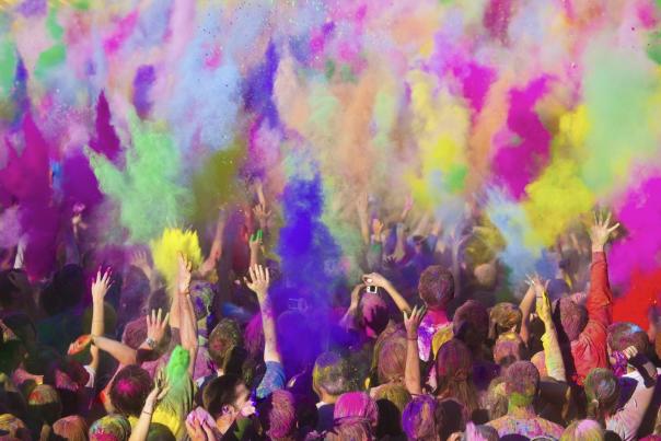 colorful chalk is thrown in air by crowd