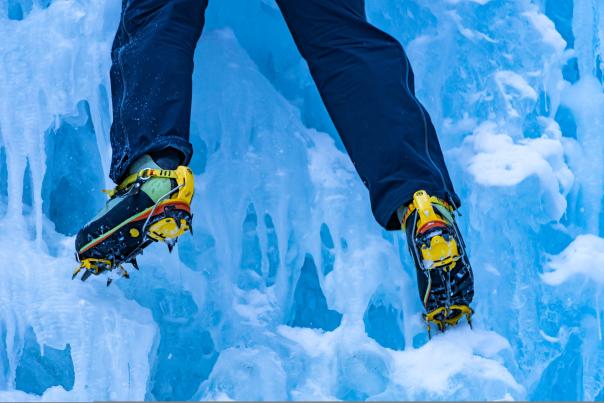 the feet and legs of an ice climber on a frozen waterfall