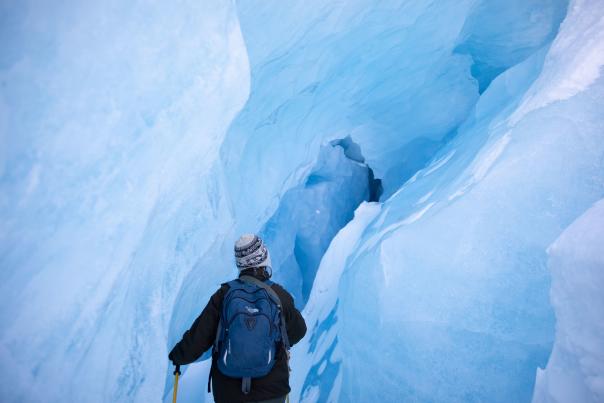 a person in winter gear stands in an ice cave