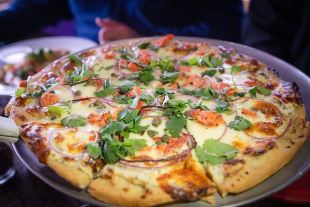 a pizza on a tray topped with smoked salmon