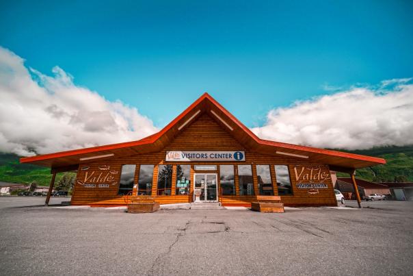 the Valdez Visitors Center with clouds, blue sky, and mountains in background