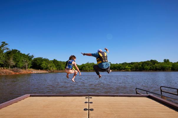 a father and son jumping into Arcadia Lake
