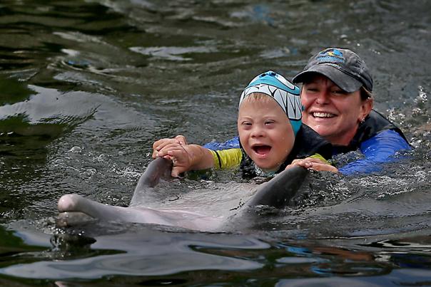 Simon Schaetzler, 6, of Nuremberg, Germany, enjoys getting to know the dolphins at Island Dolphin Care in Key Largo with an assist from Recreational Therapist Kim Severance. Simon, who has Downs Syndrome, enjoyed an early summer day of Dolphin Therapy.