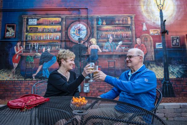 couple toasting in front of mural
