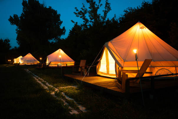 Glamping Blog Cover (4 canvas bell tents illuminated by lanterns along path in the woods)