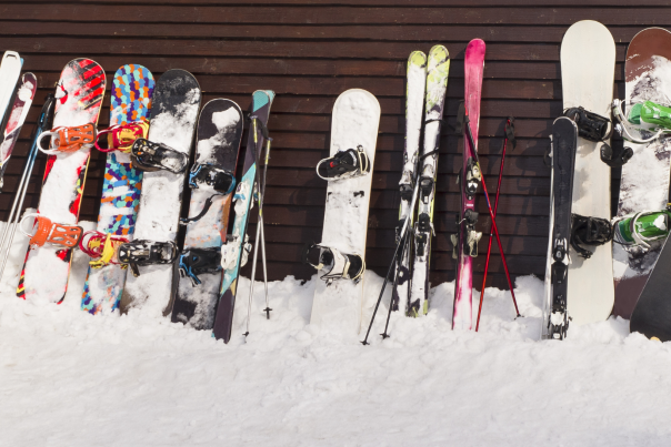 Skis and Snowboards Leaning Against a Brown Wall