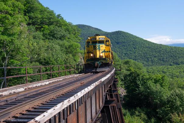 Yellow train traversing train tracks through Crawford Notch