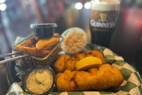 Fish fry basket with French fries, coleslaw and tartar sauce. Next to Guiness beer.