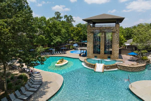 A drone photo of the pool at The Woodlands Resort, featuring a brick tower hiding two water slides into an enormous pool. Dozens of chaise chairs line the edge of the pool on the left.