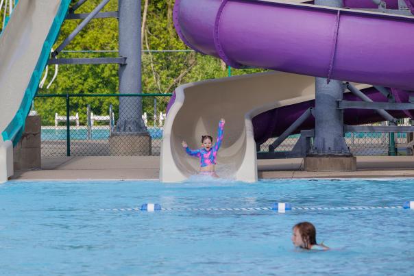 Girl with arms up riding down the purple water slide at Woodstock Water Works