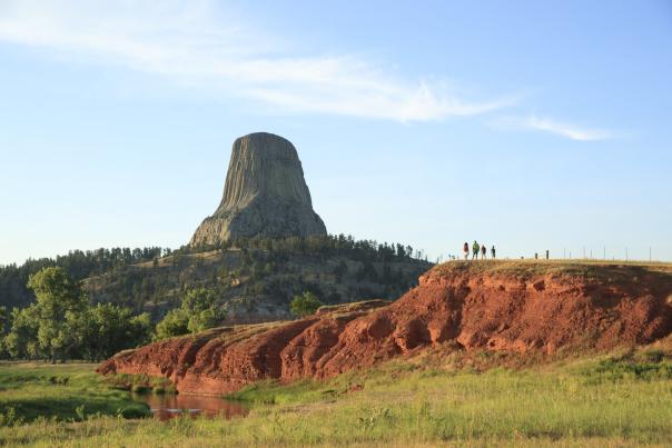 Hiker walking along a trail surrounded by lush greenery in Wyoming at sunrise