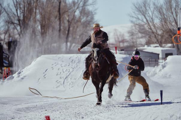 A skier is being pulled by a horse and rider during a skijoring competition in Pinedale, Wyoming.