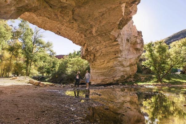 Couple walking under a natural bridge near a creek