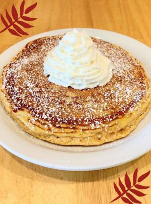 Plate of pumpkin pancakes topped with whipped cream and powdered sugar