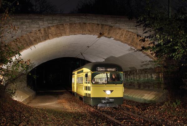 A streetcar with the words "Como - Harriet" above the window rolls through a tunnel at night