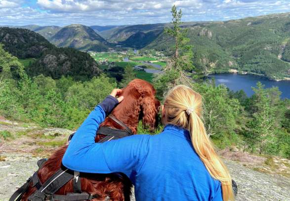 Girl and her dog on top of the mountain with view to the valley. Photo