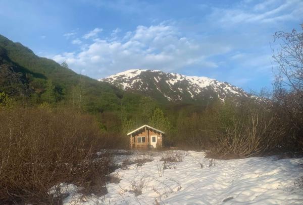 a cabin in front of a mountain; snow on ground