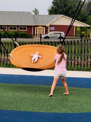 girl pushing doll on swing at playground