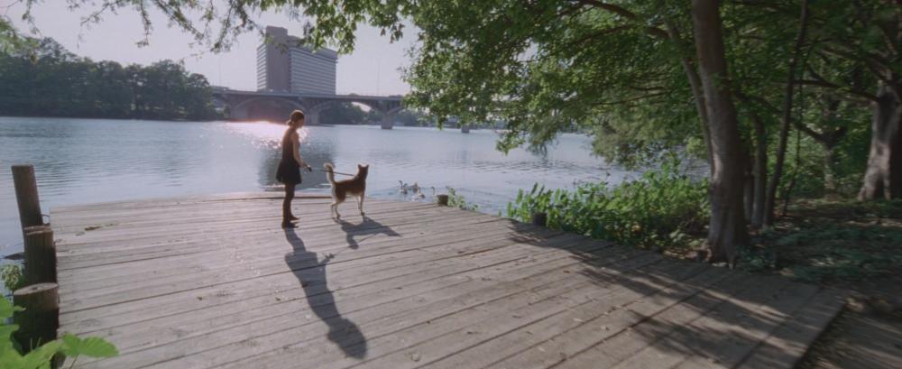 Song to Song screengrab, showing Faye and her dog on the pier along Lady Bird Lake on the Hike and Bike Trail