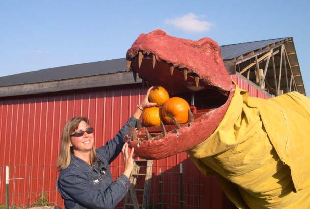 Woman with pumpkin-eating dinosaur at Great Country Farms
