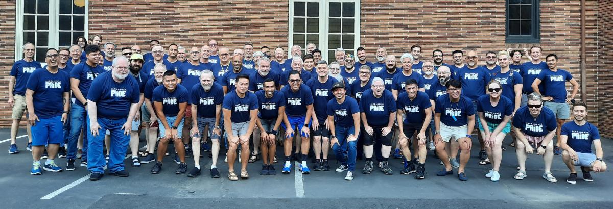 A group of Sacramento Gay Men's Chorus members in dark blue shirts with the words Sacramento Pride