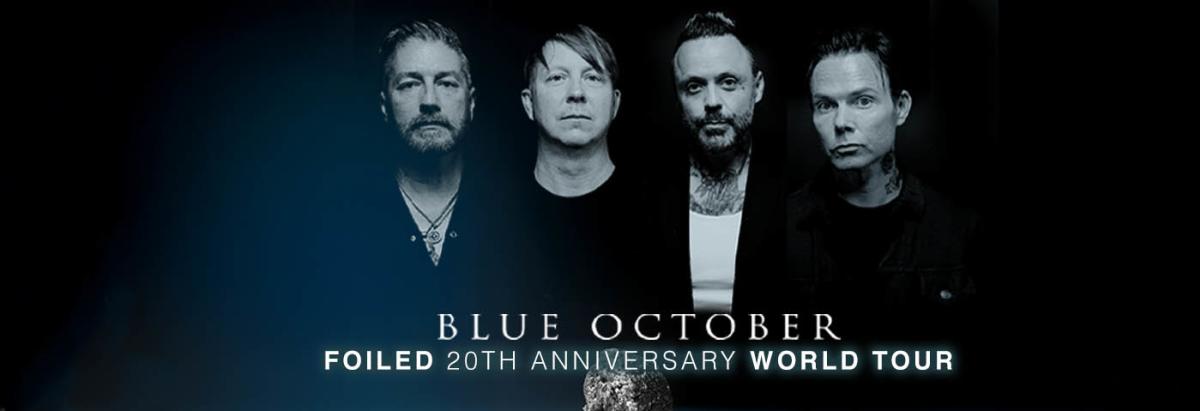 Four members of the band Blue October take a photo side by side in front of a black background