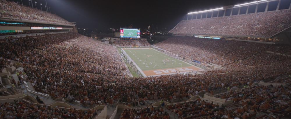 Song to Song screengrab, showing a wide-angle shot of the DKR Texas Memorial stadium during a crowded UT football game
