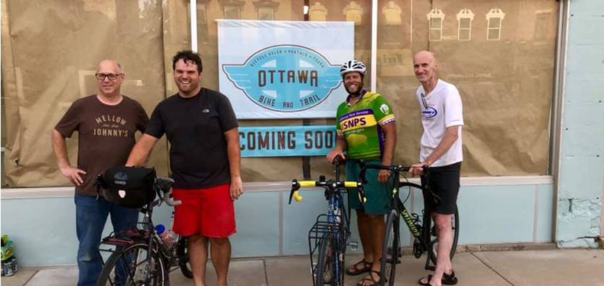Riders pose in front of the Ottawa, KS Bike Shop, opening soon