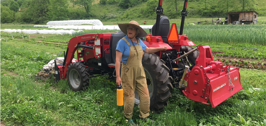 A farmer stands by a tractor during an Asheville Farm to Table Tour