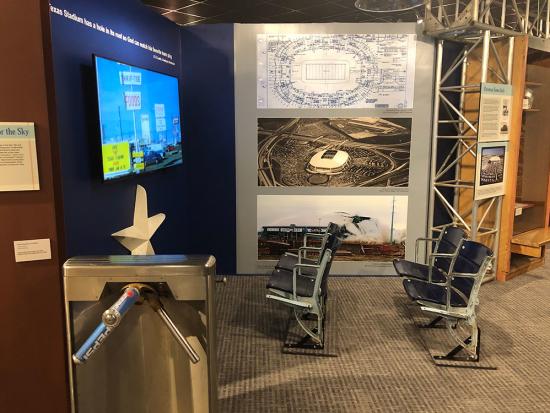 Irving Archives and Museum's Texas Stadium exhibit featuring a turnstile, seats, blue prints, a black and white poster of the stadium and a poster of the implosion