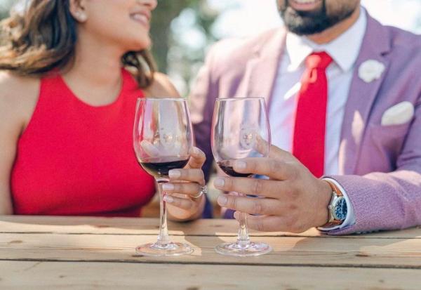 Couple holds wine glasses filled with red wine