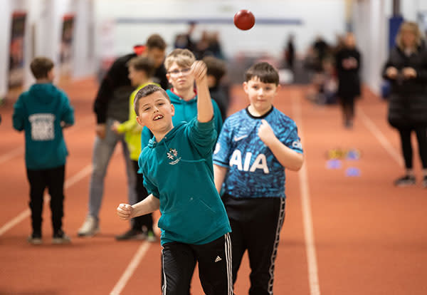 A child throwing a ball in a sports hall.