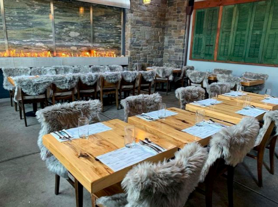 Patio seating at Mistral in Princeton, NJ with fur-covered chairs around wooden tables near a fire