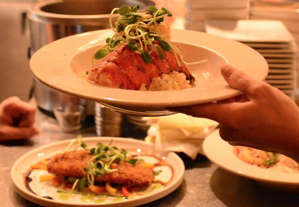 Dinner plate being handed over inside of Basi Italia's kitchen