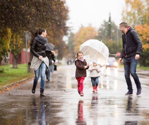 Family with umbrellas walking in the road in the rain